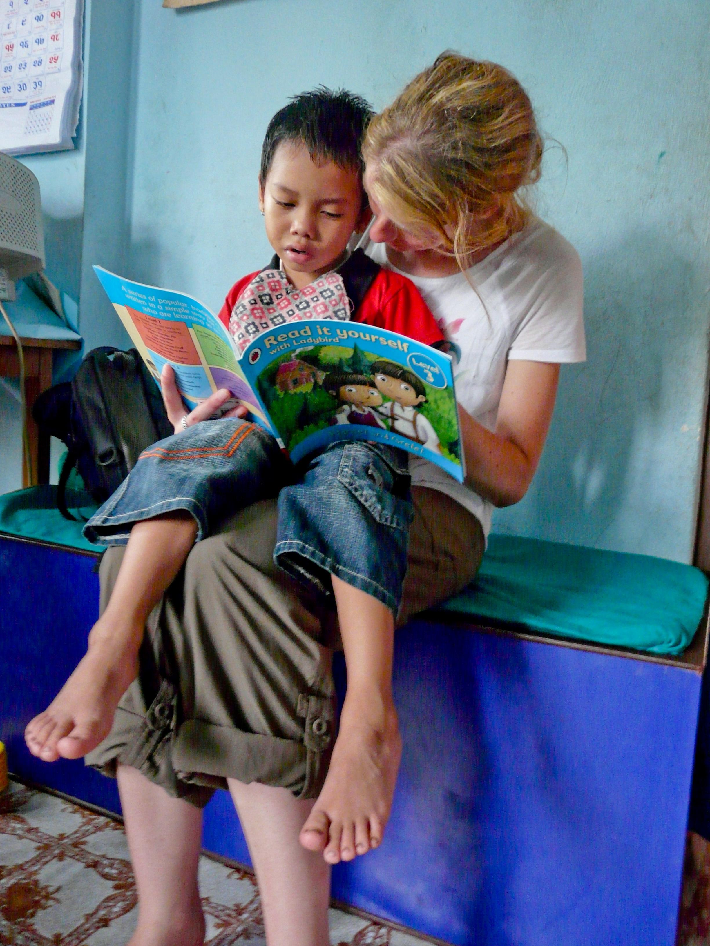 A student on the Physiotherapy internship for high school students in Nepal, reads to a young child. A child and Projects Abroad student read a book on the Physiotherapy internship for teenagers in Nepal.